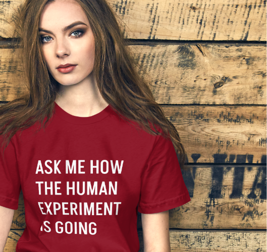 Person wearing a red t-shirt with text, sitting against a wooden wall.